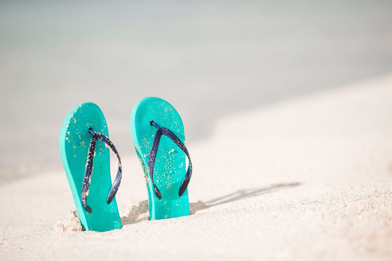 Summer mint flip flops with sunglasses on white beach